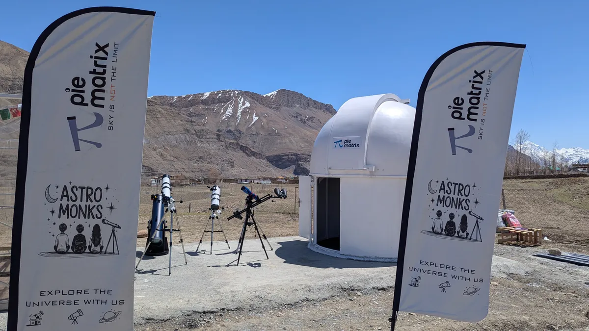 Telescopes set up in daylight beside the dome, between AstroMonks and Pie Matrix flags