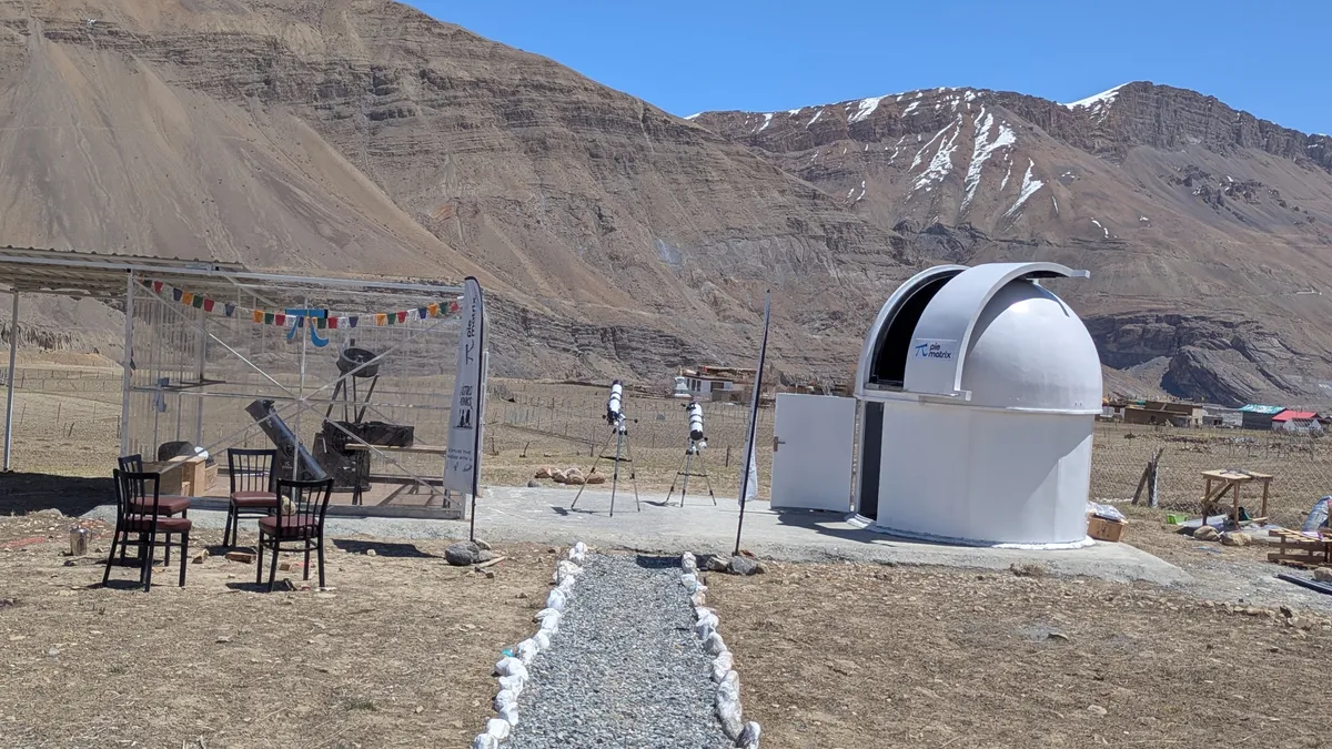 The AstroMonks observing field by day: the white dome, telescopes on the pad and mountains behind