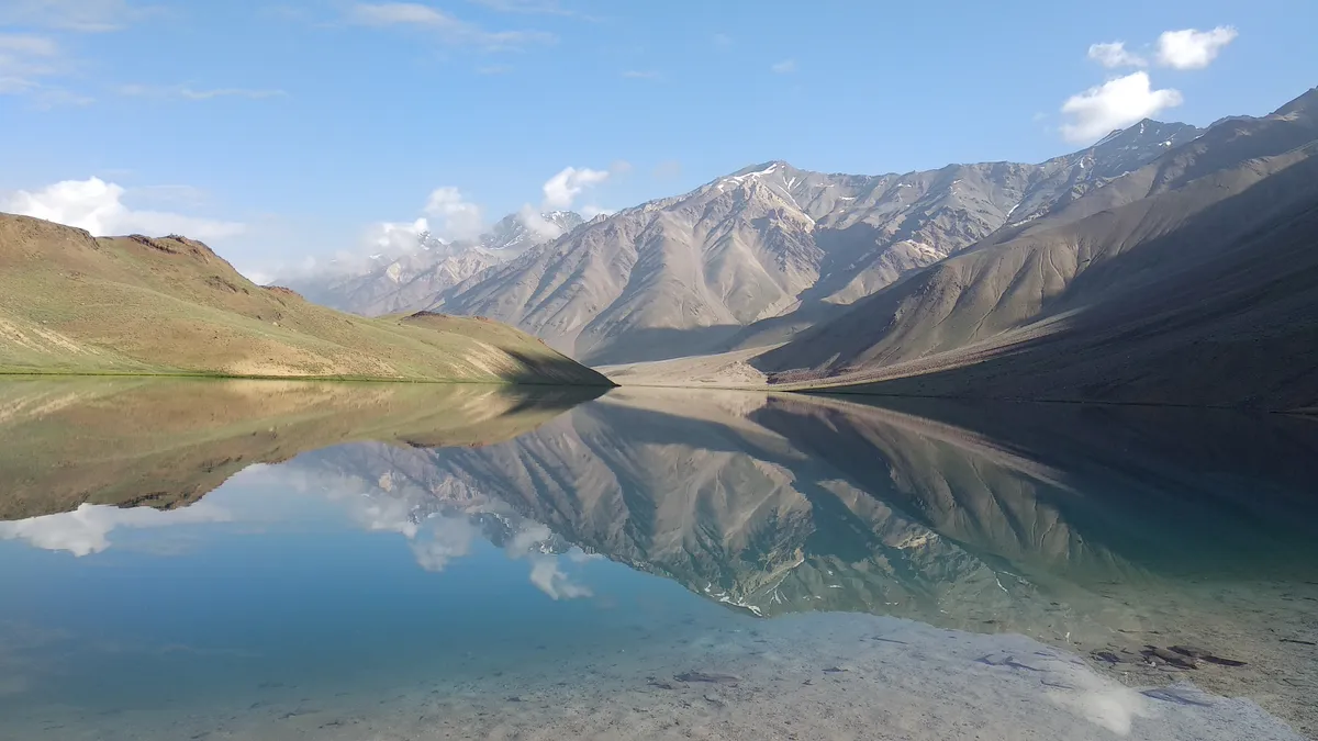 Chandratal lake mirroring the mountains around it on a still morning