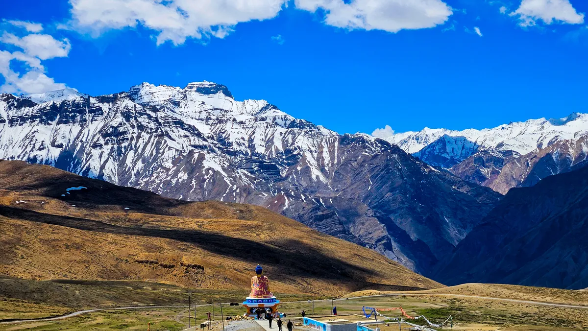 The Buddha statue at Langza seen from behind, with snow-capped peaks across the valley